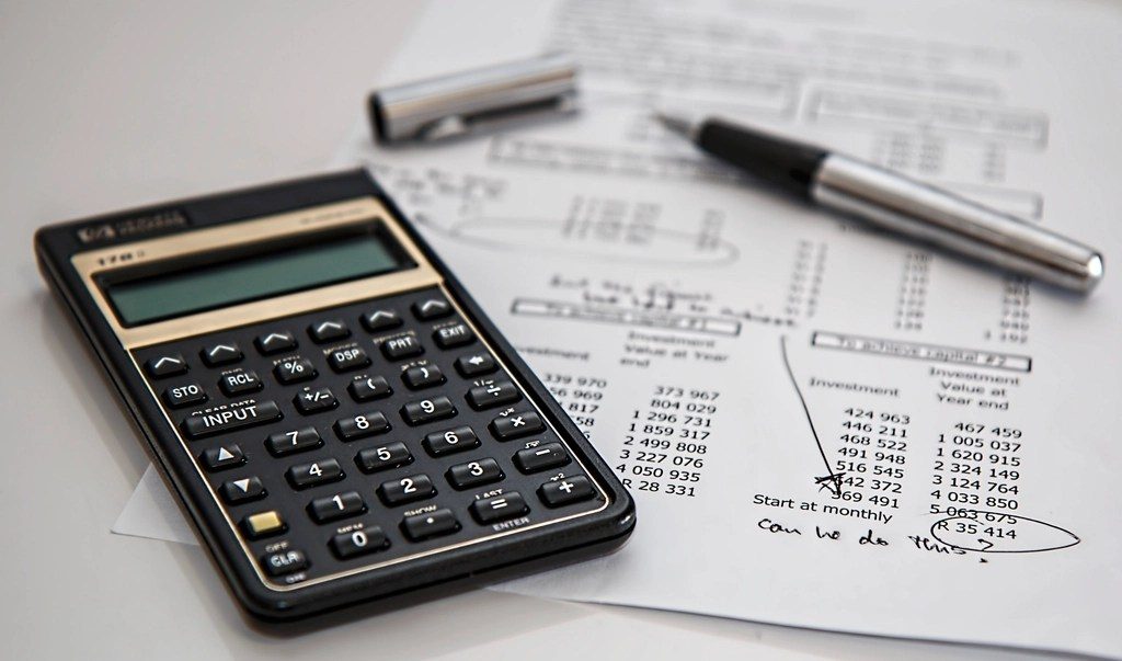 A calculator, a pen and printed accounts on a desk