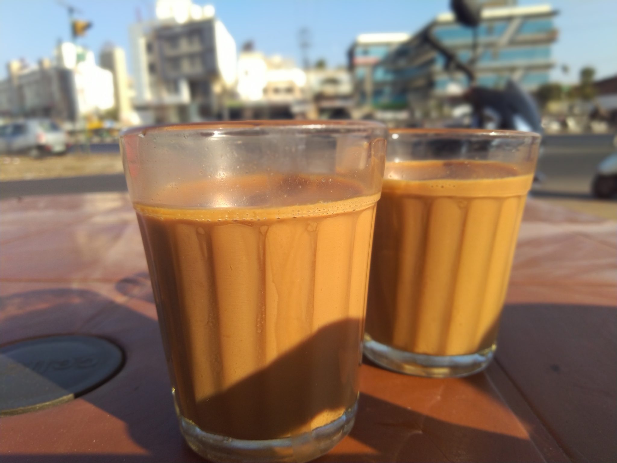 Two glasses of tea standing side by side on a table