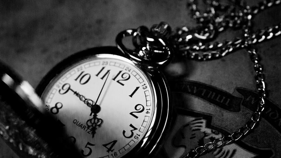 A vintage pocket watch on its chain, in black and white