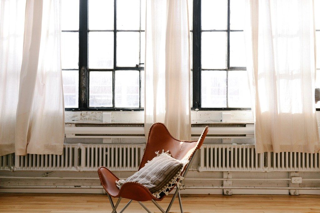 A leather armchair beside tall windows with pale curtains