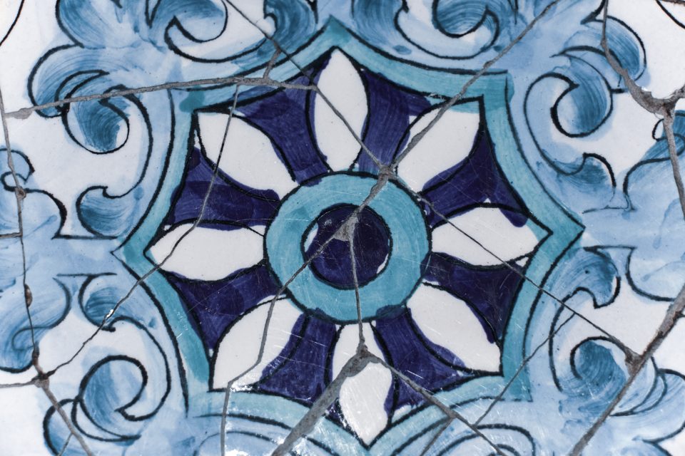 A blue and white mosaic tile with a many-petalled pattern