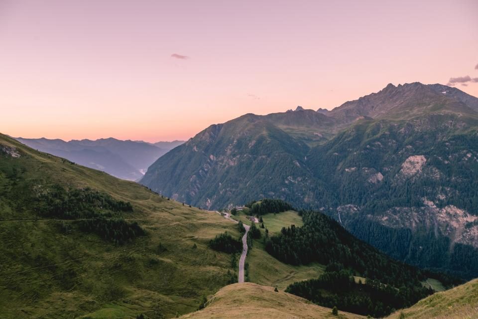 A winding path along a green highland ridge at dusk