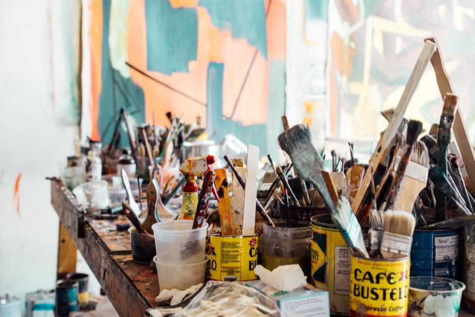 A jumble of artist's paint brushes standing in pots in a studio