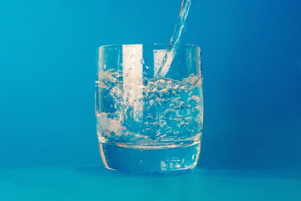 Water being poured into a glass against a bright blue background