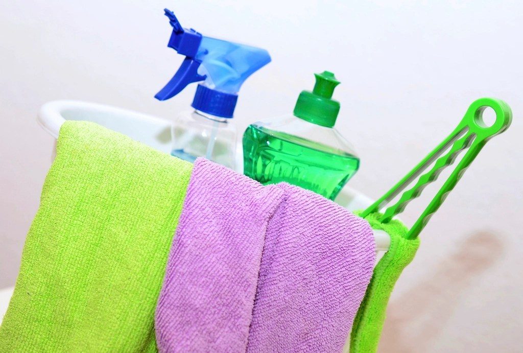 Cleaning cloths, a spray bottle and a duster in a cleaning caddy