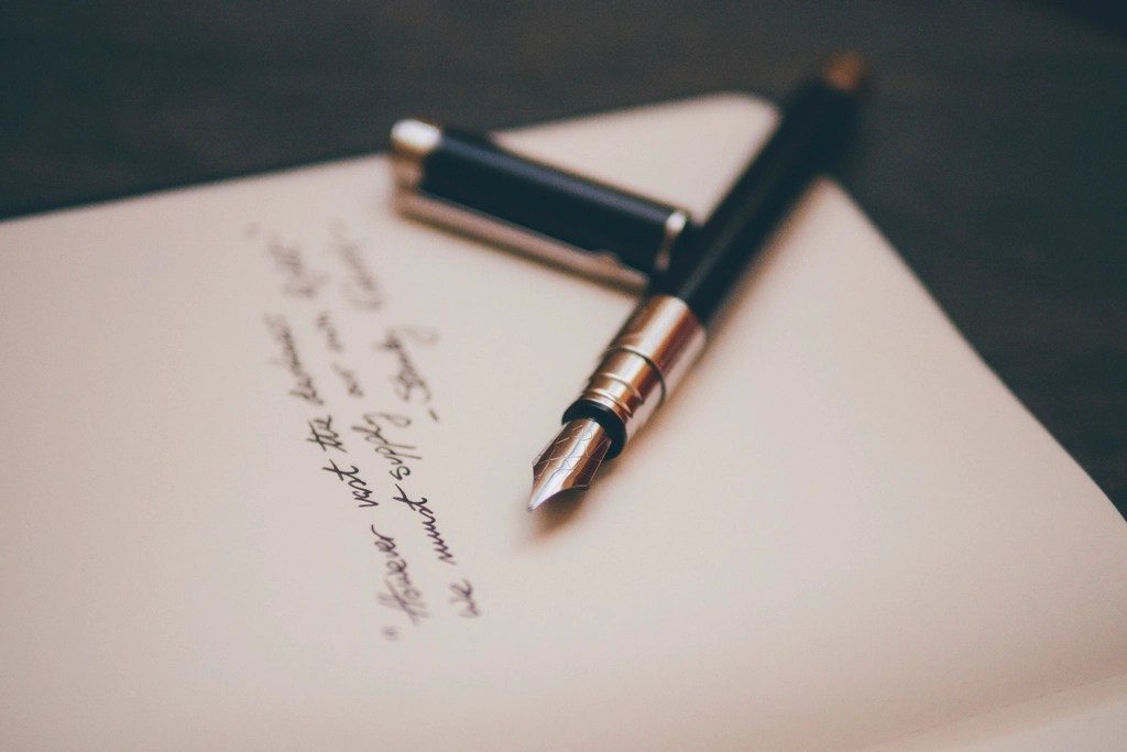 A fountain pen resting on a sheet of handwritten paper