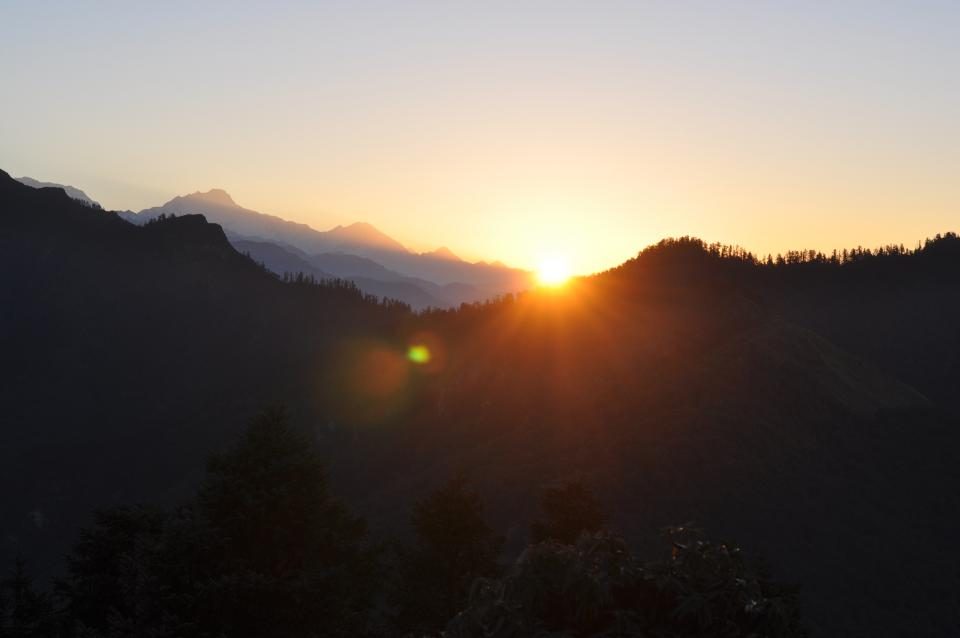 The sun rising over dark hills at dawn