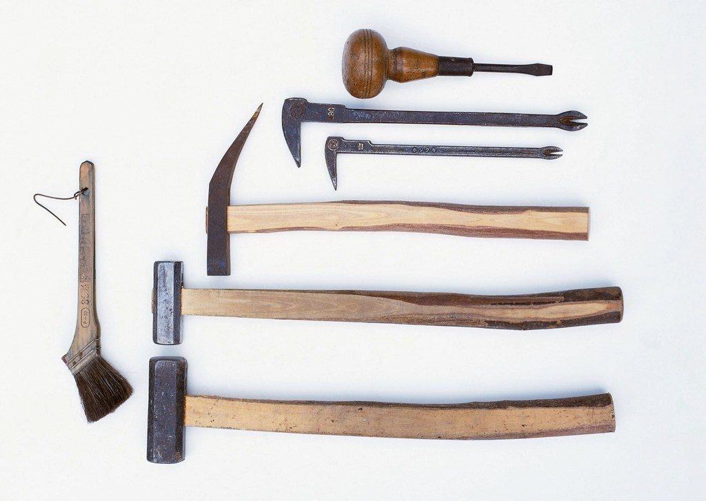 Old hand tools laid out in a row on a white surface