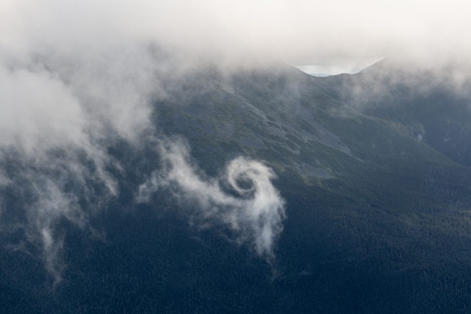 Cloud drifting over a dark mountainside