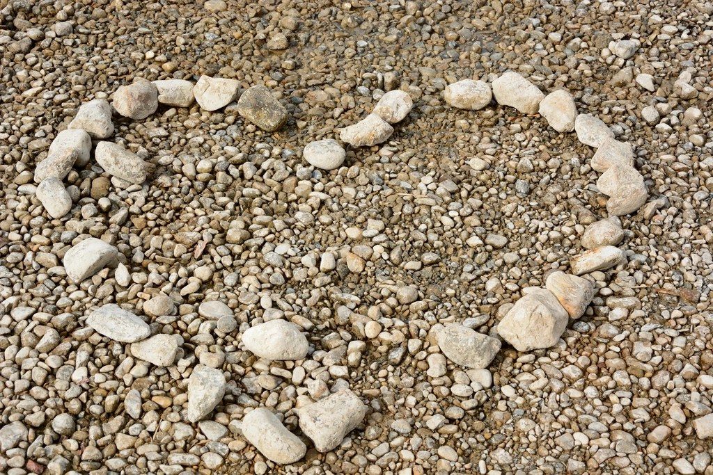 A heart shape laid out in pebbles on gravel