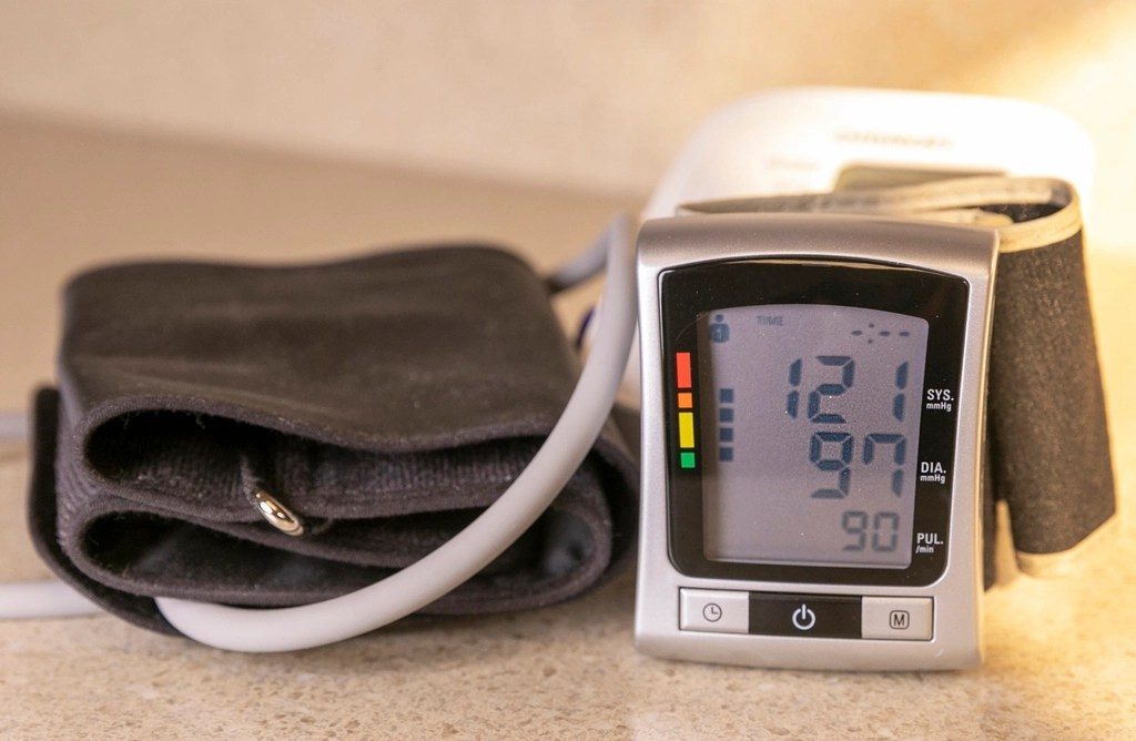A digital blood pressure monitor with its arm cuff, showing a reading
